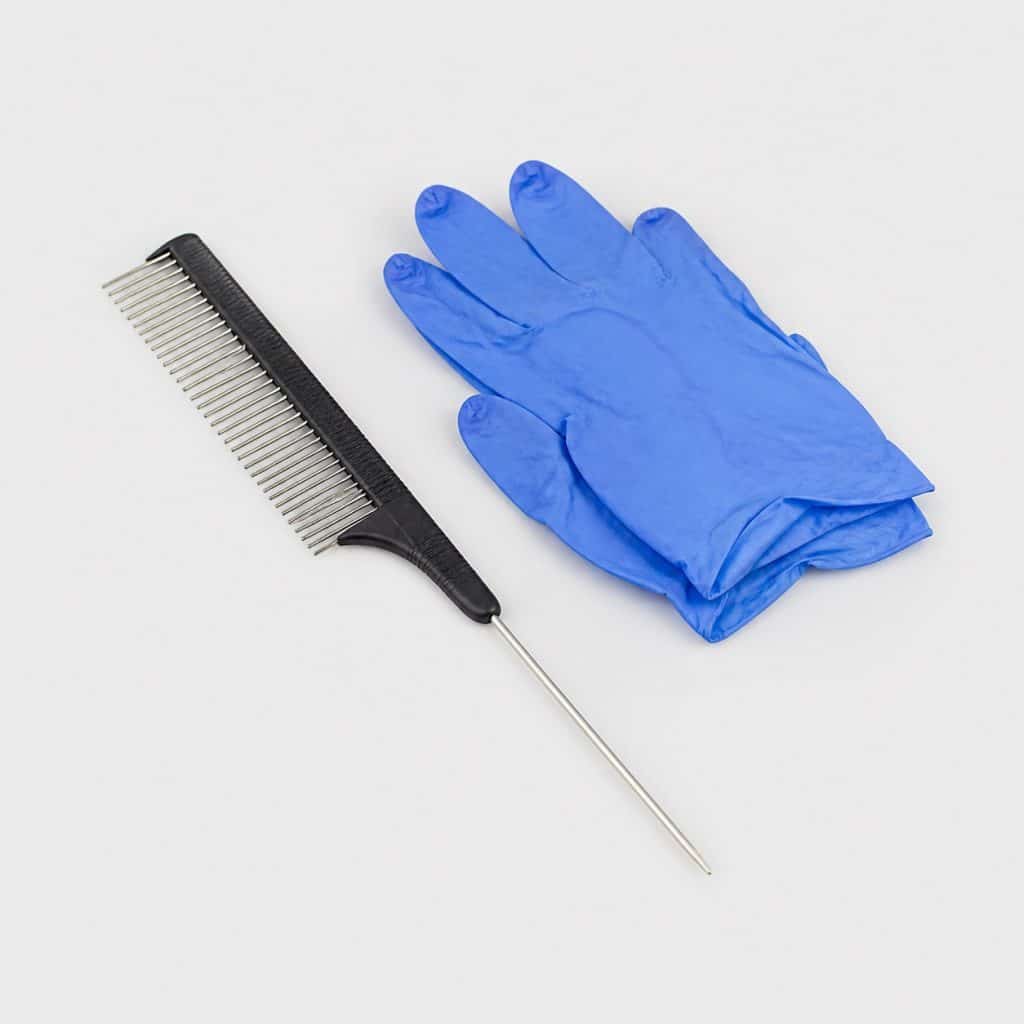 Peigne à raie en inox de 16 cm et gants jetables en nitrile posés à plat